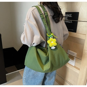 Detail of green hobo bag with striped texture and yellow flower charm on model