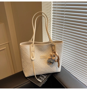 Détail du sac fourre-tout blanc cassé avec texture gaufrée et charmant ours en peluche