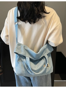Light blue large canvas crossbody tote bag with adjustable strap and patch logo