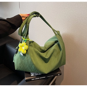 Detail of green pleated tote bag with sunflower pendant on adjustable shoulder strap
