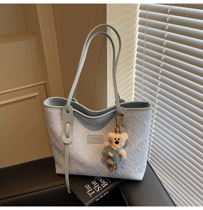 Détail du sac cabas bleu clair à motifs floraux avec breloque ours en peluche doux