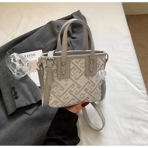 Détail du sac seau gris avec motif de labyrinthe, fleurs et pendentif à pampilles