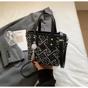 Détail du sac seau noir avec motifs grecs argentés et pompon décoratif gris chic
