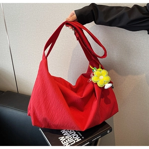 Detail of red pleated fabric tote bag featuring a bright yellow daisy charm accessory
