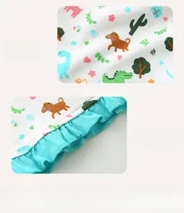 Detail showing cartoon dinosaur print fabric and blue ruffled hem on cotton girls shorts