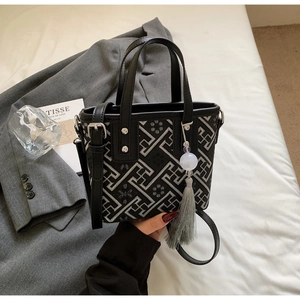 Vue détaillée du sac noir avec broderie géométrique argentée et accessoire pompon décoratif