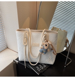 Détail du cabas en jacquard blanc avec étiquette MaishaKeke et breloque ours en peluche