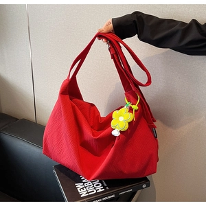 Macro shot of red pleated nylon tote bag featuring a bright yellow flower charm detail