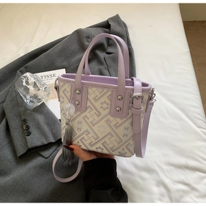 Détail d'un sac seau brodé lavande avec motifs géométriques et pendentif gland