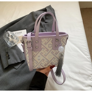 Détail du mini sac seau brodé lilas avec poignées en cuir et long gland décoratif
