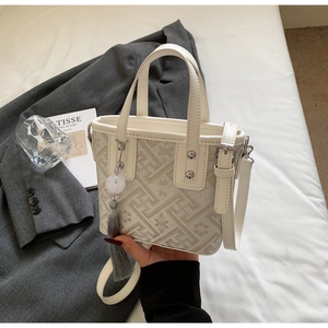 Détail des motifs floraux brodés sur un sac cabas crème avec breloque à pompon chic