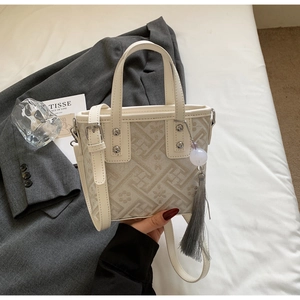 Détail d'un sac seau minimaliste avec motifs géométriques, bordure en cuir et pompon