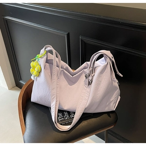 Detail of light purple pleated canvas handbag with a yellow flower charm on a chair