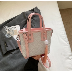 Sac seau rose avec motif géométrique sur un lit avec blazer et décoration