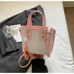 Détail d'un sac seau rose et blanc avec motifs floraux, géométriques et gland décoratif