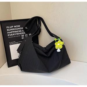Detail of black pleated hobo bag with textured fabric and yellow flower charm