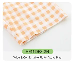 Detail of loose-fit orange plaid shorts showing hem stitching and breathable fabric