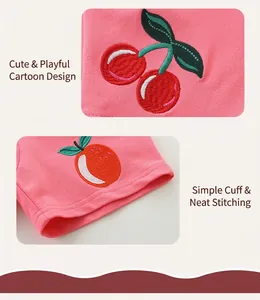Détail du short en coton rose montrant une broderie de fruits et un ourlet bien cousu