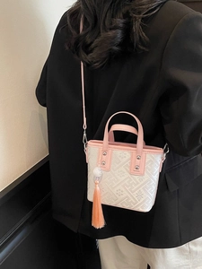 Sac seau en cuir rose avec tissu floral et long gland sur un mannequin femme