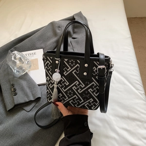 Detailed view of embroidery bucket bag with grey geometric patterns and elegant tassel