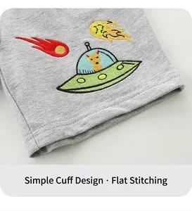 Detailed close-up of boy's grey cotton shorts with cartoon UFO embroidery and neat stitching