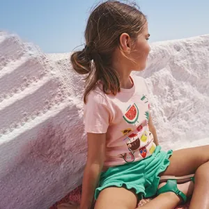 Detailed view of pink cotton t-shirt with fruit print and green ruffled summer shorts