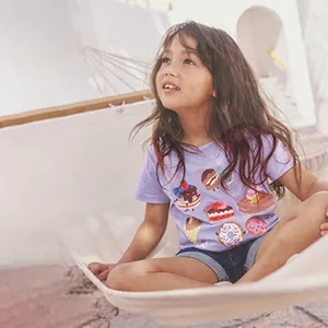 Detail of a girl in a purple T-shirt with sweet dessert prints and denim shorts in a hammock