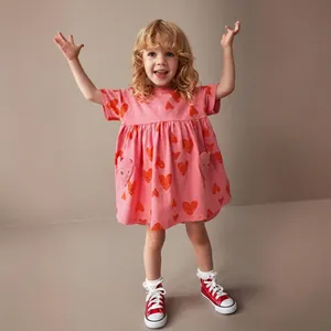 Detail of girls pink cotton dress with red heart prints and pleated puffy skirt