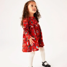 Petite fille portant une robe de Noël rouge festive avec des motifs de fleurs d'hiver