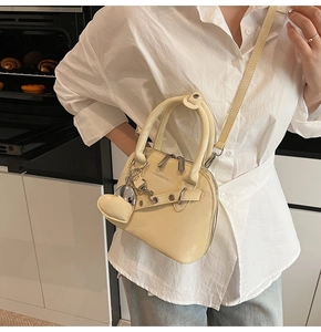 Détail du sac coquillage crème présentant un charm miroir unique en forme de cœur