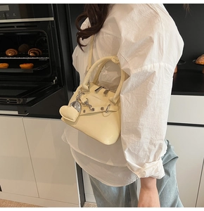 Détail du sac beige avec breloque cœur et œillets métalliques dans une cuisine moderne