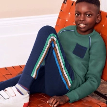 Détail d'un sweat vert foncé et d'un pantalon bleu marine avec des rayures colorées