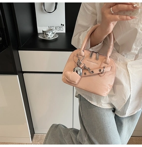 Détail du sac coquille en cuir verni rose avec rivets et pendentif en forme de cœur
