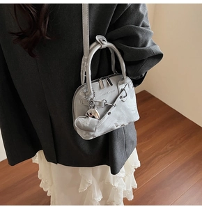 Détails du sac à main argenté métallisé avec doubles zips et breloque en cœur