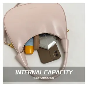 Macro view of pink crescent bag showing spacious interior with phone and cosmetics