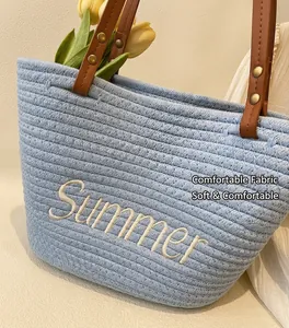 Close-up of summer woven tote with light blue straw texture and leather handles