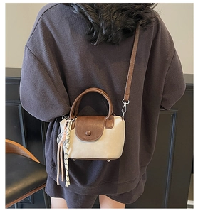 Model wearing a vintage crossbody bag in beige fabric with brown leather trim detailing