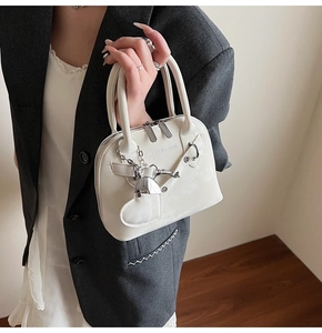 Détail d'un sac à main blanc verni avec pendentif en cœur et chaîne argentée chic