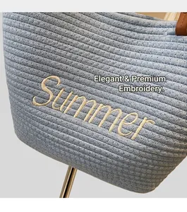 Close-up of sky blue straw bucket bag featuring Summer embroidery and leather handle
