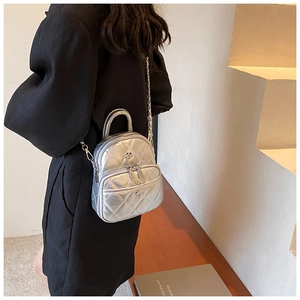 Detail of silver quilted mini bag with metal chain strap and floral emblem