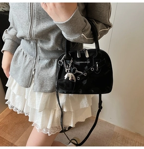 Gros plan du sac à main rétro noir avec détails argentés et pendentif cœur sur mannequin