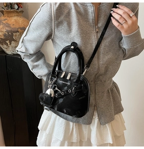 Gros plan du sac coquillage noir avec texture marbrée et détail de breloque en cœur