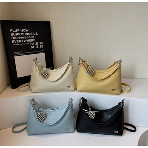 Detail of four textured leather dumpling bags in white, yellow, blue, and black with charms