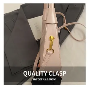 Close-up of pink underarm bag featuring golden metal swivel hooks and side stitching details