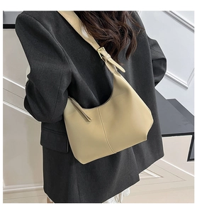 Detail of minimalist beige shoulder bag with golden buckle on a grey blazer outfit