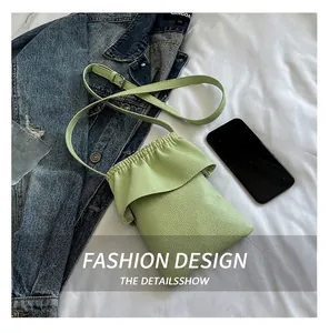Détail du sac seau en cuir vert clair à texture litchi avec fermeture à cordon volantée