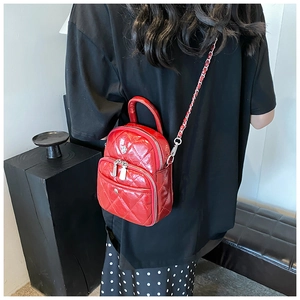 Détail d'un sac bandoulière matelassé rouge avec fermetures éclair et rivets argentés