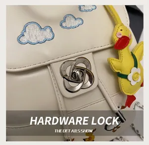 Detail der blumenförmigen Silberschnalle und Wolkenstickerei auf cremefarbener Tasche