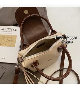 Detailed shot of smooth metal zipper and magnetic flap closure on two-tone crossbody bag