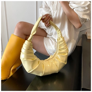 Close-up of pleated yellow hobo bag with glossy finish and metal zipper detail
